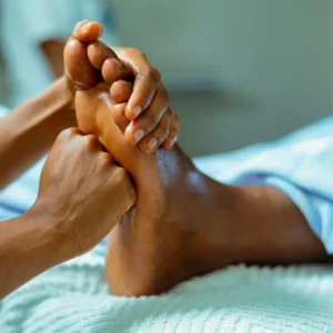 Demostración profesional de reflexología podal con presión manual sobre el pie